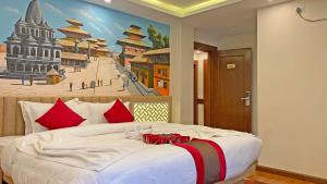 加德满都Hotel Malati的卧室配有一张大床,墙上挂有绘画作品
