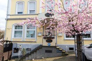 BetzdorfHotel Royal的一座有楼梯的建筑和一棵有粉红色花卉的树