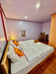 巴色Heaven Guesthouse的一间卧室配有一张带白色床单和黄色枕头的大床。