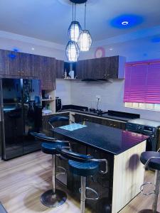 贝宁城Dsmarts apartments的厨房配有黑色台面和吧台凳