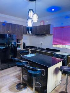 贝宁城Dsmarts apartments的厨房配有黑色台面和吧台凳
