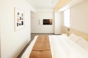 大阪Shin-Osaka Station Hotel的一间卧室配有一张床,墙上配有电视