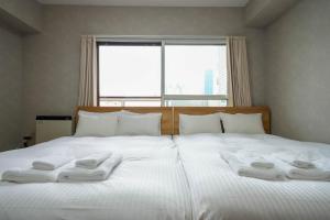 札幌Residence Hotel KABUTO的一张带白色毛巾的床,配有窗户