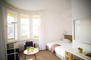诺德奈Hotel Haus Norderney的卧室配有床、桌子和窗户。