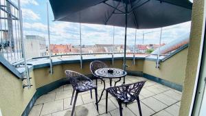 慕尼黑ARABEST Aparthotel & Boardinghouse的阳台配有桌椅和遮阳伞。