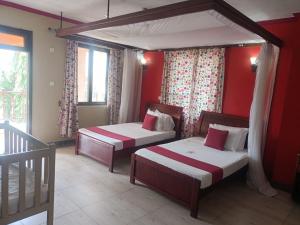 姆特瓦帕蒙巴萨黏巴达度假村的宿舍间的两张床,设有红色的墙壁和窗户