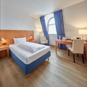 特里尔特里尔城市贝斯特韦斯特酒店的酒店客房配有一张床、一张书桌和一张书桌。
