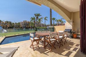 圣罗克Waterside Apartment in Sotogrande Marina with Private Pool的游泳池旁带桌椅的天井