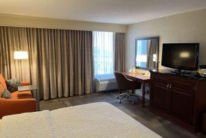 圣安Wingate by Wyndham St Louis Airport的酒店客房配有一张床和一张书桌及一台电视