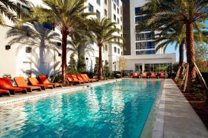 奥兰多万豪奥兰多诺娜湖万怡酒店的一个带橘子椅和棕榈树的游泳池