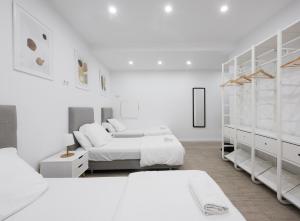 巴塞罗那巴塞罗那中心无限旅舍的一间白色卧室,配有两张床和白色的橱柜