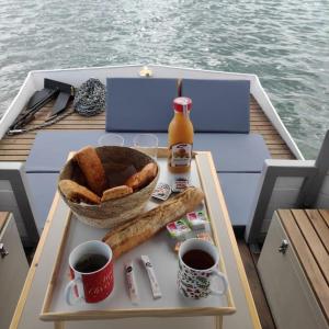 雷日卡普费雷Bateau logement nuit Insolite Astragale的船上的餐桌,包括面包和饮料