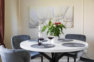 布达佩斯Stock Room apartman的一张带两杯葡萄酒和花瓶的白色桌子