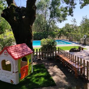 贝哈尔Casa Rural Viñas Perdidas的玩具狗屋和树旁的长凳