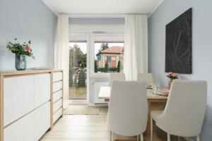 波兹南Apartment with garden Wolkowyska by Renters的一间带桌子和白色椅子的用餐室