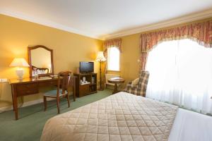利敦瓦纳Sheedys Boutique Hotel & Restaurant的酒店客房带一张床、一张书桌和一面镜子