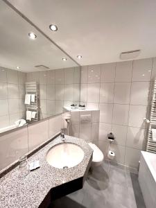 欣特察尔滕Hotel Sonnenberg Garni的一间带水槽、卫生间和镜子的浴室