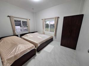 SuwannaphumPPN Garden Resort的一间卧室配有两张床、一个橱柜和两个窗户。