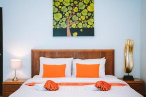 拉扬海滩度Layantara Resort, Phuket的一间卧室配有带橙色枕头和绘画的床。