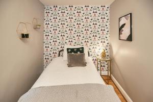 LindleyHost & Stay - Cobble Cottage的小卧室配有一张带花卉壁纸的床