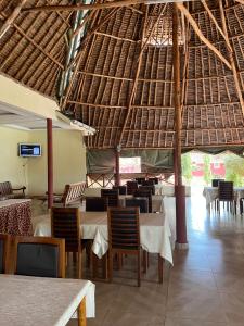 Tsavo West National ParkLake Jipe Eco Lodge的一间带桌椅和稻草屋顶的餐厅