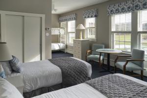 Sebasco Estates希巴斯科港度假酒店的酒店客房带两张床和一张桌子以及椅子。