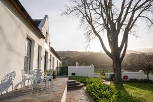 帕尔Laborie Jonkershuis的庭院配有白色椅子和树