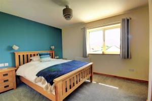 奥克尼Aurora - Self Catering, Kirkwall, Quiet Location with Luxury Hot Tub的一间卧室设有一张木床和一个窗户。
