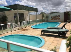 莫索罗Apartamento em Mossoró的庭院设有2个大型游泳池,配有2张躺椅