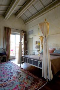 拉文纳Au petit jardin的一间卧室设有一张天蓬床和大窗户