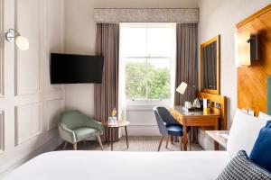 爱丁堡voco Edinburgh - Royal Terrace, an IHG Hotel的配有一张床、一张书桌和一扇窗户的酒店客房