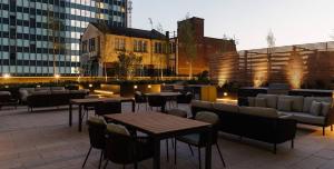 伯明翰The Mercian Luxury Apartments Birmingham City Centre - Your Perfect Stay Apart hotels- 24 Hour Gym Rooftop Terrace Cinema Room的一个带桌椅的屋顶露台,位于大楼内