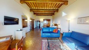 卡斯特利纳-因基安蒂帕拉佐斯奎西亚酒店的客厅配有蓝色的沙发和电视