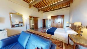卡斯特利纳-因基安蒂帕拉佐斯奎西亚酒店的一间卧室配有一张床、一张沙发和一面镜子