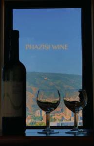第比利斯Phazisi Hotel的两杯葡萄酒,旁边是一瓶葡萄酒