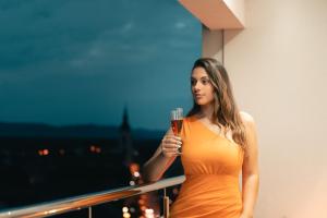 KriževciApartman Panorama的穿着橙色衣服的女人,拿着一杯葡萄酒