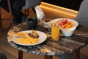 梅里达Ontico Urban Design Hotel的一张桌子,上面放着两盘食物和一杯橙汁