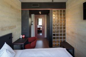 圣加仑Tailormade Hotel LEO St Gallen的一间卧室配有一张床和一张书桌,墙上装有葡萄酒瓶