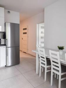 克拉科夫Apartment Szwed-Sniadowskiej Residence的厨房配有带白色椅子的桌子和冰箱。