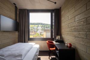 圣加仑Tailormade Hotel LEO St Gallen的一间卧室配有一张床、一张书桌和一个窗户。