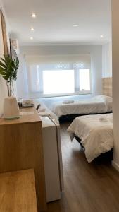 里奥夸尔托Apart IMEB spa & wellness的客房设有两张床、一张桌子和一个窗户。
