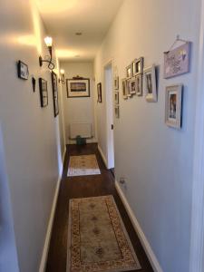塔拉莫尔Coreen Guest House的走廊上设有白色墙壁,上面有图片和地毯