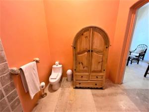萨尤利塔Villa Amor的橙色的浴室设有卫生间和木门