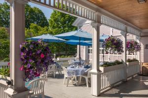 沃特伯里老驿站马车住宿加早餐旅馆的庭院配有桌子、蓝色遮阳伞和紫色鲜花。