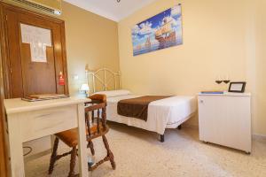 隆达科隆酒店的一间小卧室,配有一张床、一张书桌和一张书桌