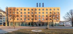 柏林Essential by Dorint Berlin-Adlershof的前面有树木的大型砖砌建筑