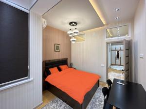 杜尚别Dushanbe City View Apartments的一间卧室配有带橙色床单和桌子的床