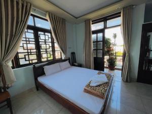 邦美蜀Manh Hung Hotel的卧室设有一张大白色的床和大窗户