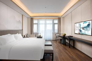 杭州杭州君尚云郦酒店的酒店客房设有一张白色大床和一张书桌