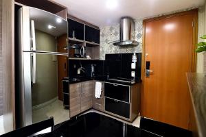 马瑙斯Tropical Executive 1006的厨房配有黑色橱柜和不锈钢冰箱
